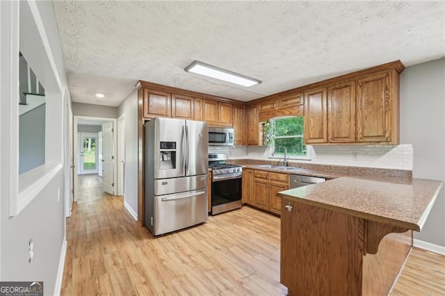 3880 Dial Mill Rd NE, Conyers, GA 30013 - kitchen with appliances with stainless steel finishes, a sink, a peninsula, brown cabinetry, and a textured ceiling