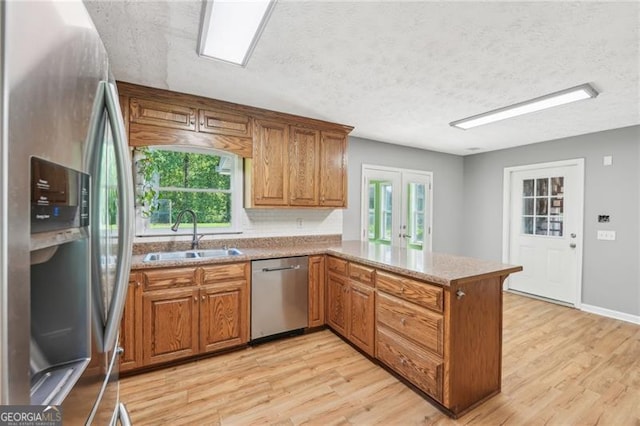 3880 Dial Mill Rd NE, Conyers, GA 30013 - kitchen featuring stainless steel appliances, a sink, a peninsula, light wood-style floors, and a textured ceiling