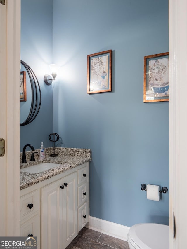 half bathroom with vanity, toilet, and baseboards