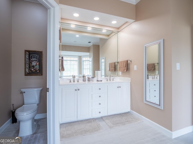 full bath with double vanity, toilet, a sink, baseboards, and ornamental molding