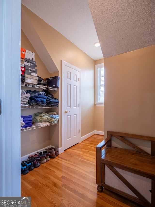mudroom with a textured ceiling, baseboards, and wood finished floors