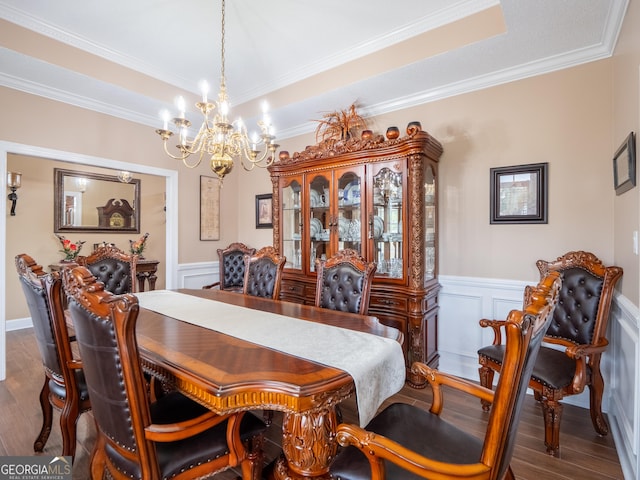 dining area with wainscoting, a chandelier, ornamental molding, and dark wood-style flooring