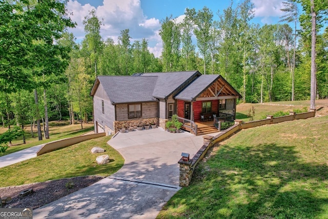 view of front of property with covered porch, roof with shingles, driveway, and a front yard