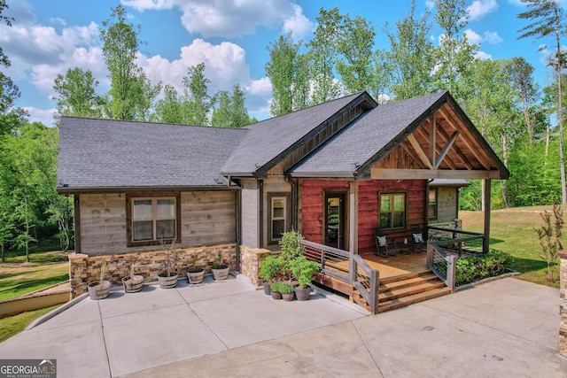 view of front of property featuring a wooden deck and roof with shingles