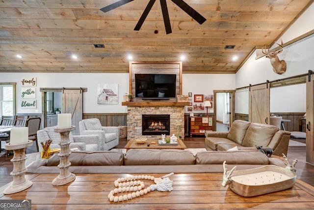 living area featuring a wainscoted wall, wood finished floors, a barn door, and wood ceiling