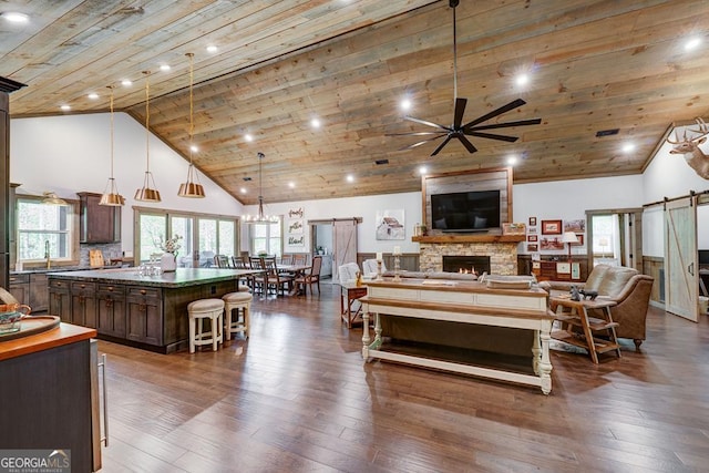 living room with ceiling fan, wooden ceiling, dark wood-style flooring, and a stone fireplace