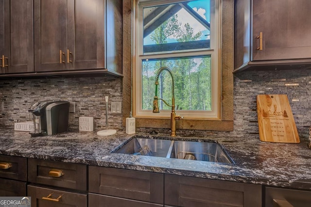 kitchen featuring dark stone counters, dark brown cabinetry, tasteful backsplash, and a sink