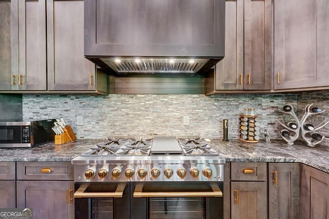 kitchen featuring premium range hood, stone counters, backsplash, and appliances with stainless steel finishes