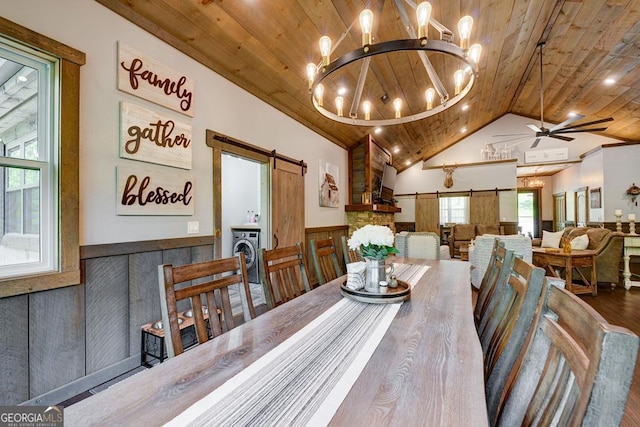 dining area with lofted ceiling, a barn door, wooden ceiling, ceiling fan with notable chandelier, and washer / dryer