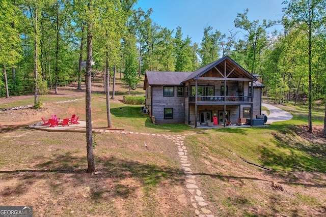 rear view of property with a lawn, stone siding, and a wooden deck