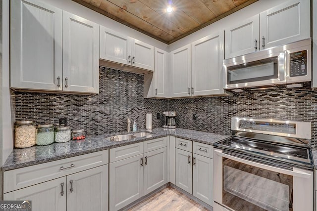 kitchen with a sink, dark stone countertops, light wood finished floors, wood ceiling, and appliances with stainless steel finishes