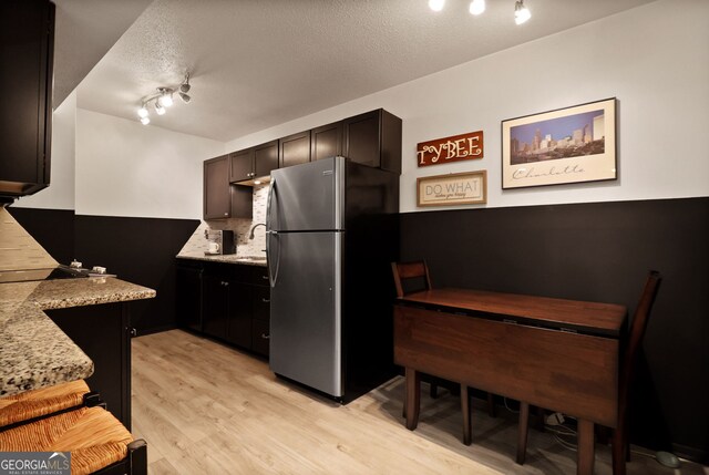 401 N Cromwell Rd Unit 6K, Savannah, GA 31410 - kitchen with light wood-style flooring, a sink, freestanding refrigerator, a textured ceiling, and light stone counters