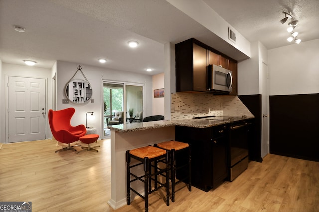 401 N Cromwell Rd Unit 6K, Savannah, GA 31410 - kitchen with stainless steel microwave, a kitchen breakfast bar, visible vents, black / electric stove, and light wood-style floors