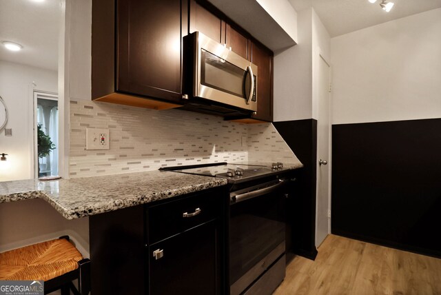 401 N Cromwell Rd Unit 6K, Savannah, GA 31410 - kitchen featuring backsplash, stainless steel microwave, light stone countertops, and electric range