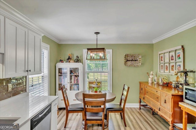 dining space featuring crown molding, light wood-style flooring, and baseboards
