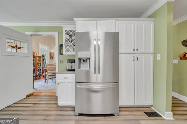 kitchen with light wood-type flooring, stainless steel fridge with ice dispenser, white cabinets, and crown molding
