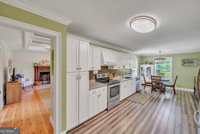 kitchen featuring light wood-style flooring, white cabinets, backsplash, appliances with stainless steel finishes, and premium range hood
