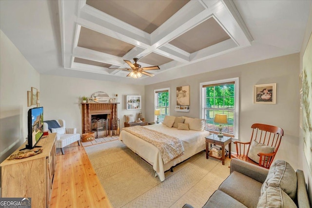 bedroom with a fireplace, ceiling fan, light wood-style flooring, beamed ceiling, and coffered ceiling
