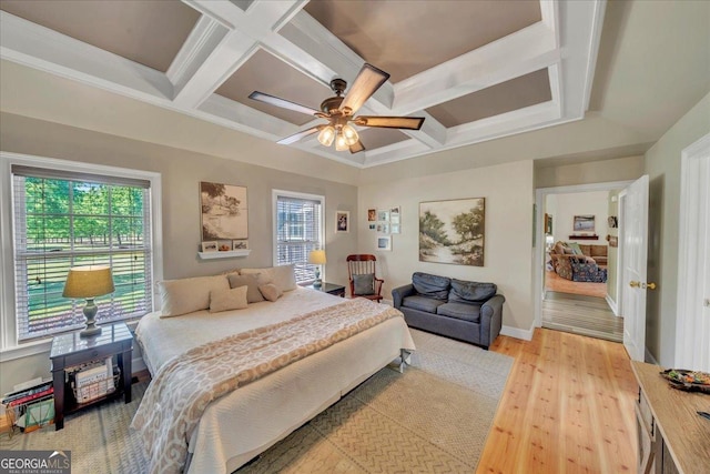 bedroom with coffered ceiling, light wood-type flooring, and multiple windows