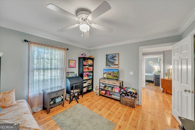 recreation room featuring light wood-type flooring, a ceiling fan, and ornamental molding