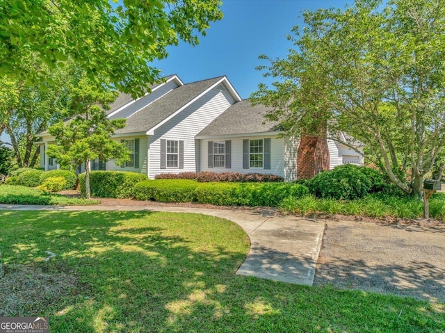 view of front of house featuring a shingled roof and a front lawn