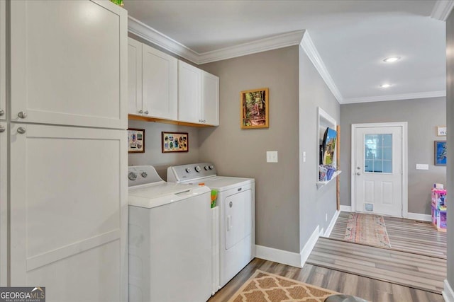 clothes washing area featuring washing machine and dryer, light wood-style flooring, cabinet space, crown molding, and baseboards