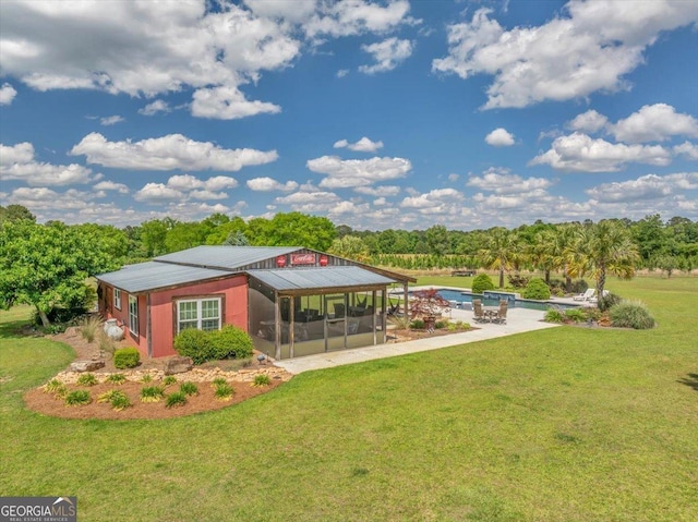 rear view of house featuring a yard, a sunroom, and an outdoor pool