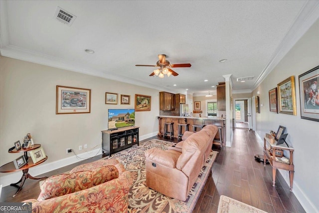 living room featuring baseboards, ornamental molding, visible vents, and dark wood-style floors