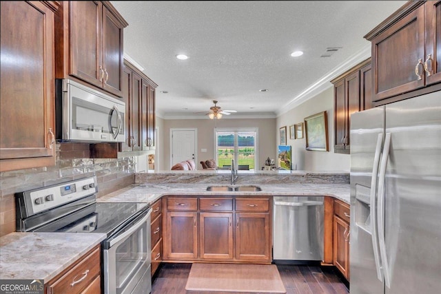 kitchen with a sink, ornamental molding, dark wood finished floors, a ceiling fan, and appliances with stainless steel finishes