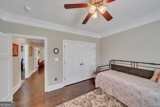 bedroom with a closet, ornamental molding, ceiling fan, wood-type flooring, and baseboards