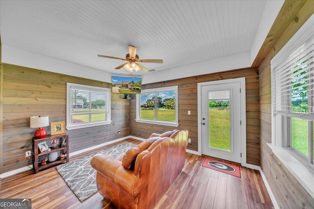 living room with wood walls, wood ceiling, hardwood / wood-style floors, and a ceiling fan