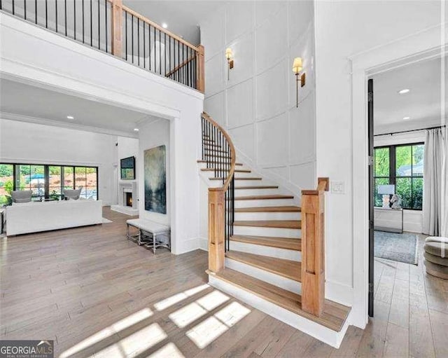 stairway with recessed lighting, baseboards, hardwood / wood-style flooring, and a towering ceiling