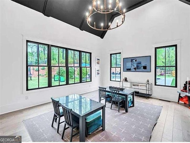 dining area with a wealth of natural light, a notable chandelier, high vaulted ceiling, and wood finished floors