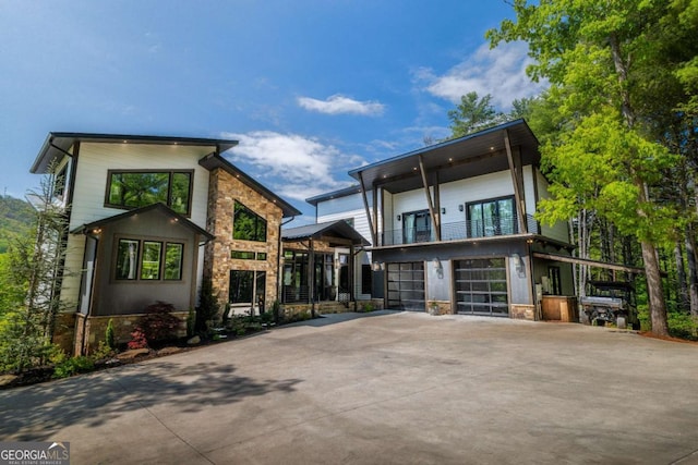 51 Birdseye Vw, Blue Ridge, GA 30513 - contemporary house featuring stone siding, concrete driveway, an attached garage, and a balcony