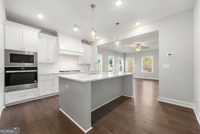 kitchen featuring a sink, baseboards, light countertops, appliances with stainless steel finishes, and custom exhaust hood