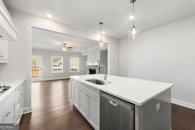 kitchen featuring baseboards, a fireplace, a sink, and stainless steel dishwasher
