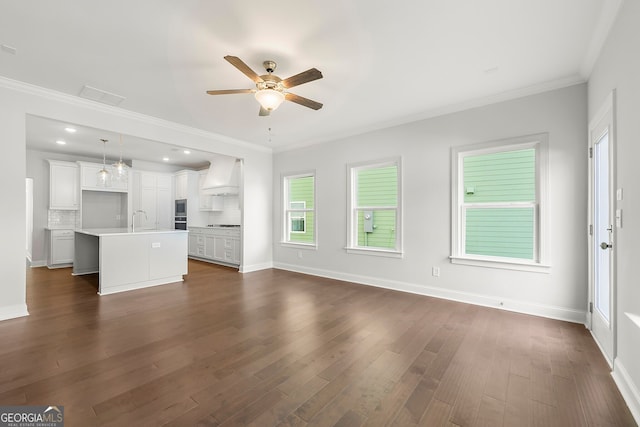 unfurnished living room with a ceiling fan, baseboards, a sink, crown molding, and dark wood-style floors