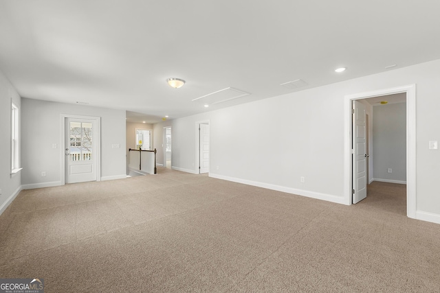 unfurnished living room featuring light colored carpet, attic access, baseboards, and recessed lighting