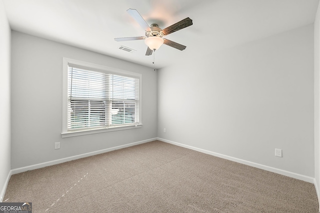spare room with carpet, visible vents, baseboards, and a ceiling fan