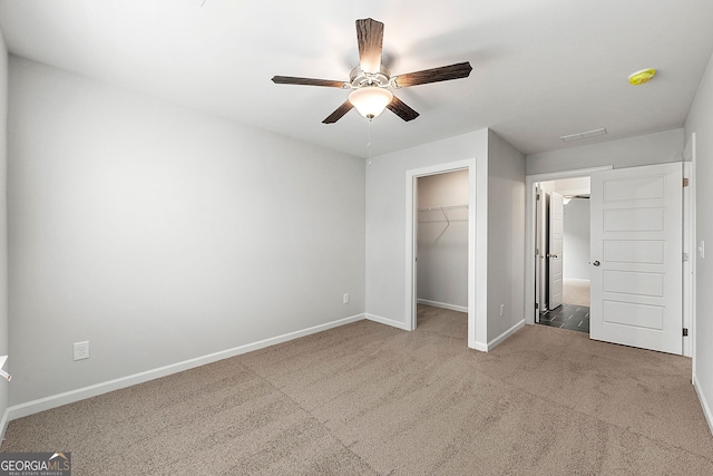 unfurnished bedroom featuring a closet, a spacious closet, carpet floors, a ceiling fan, and baseboards