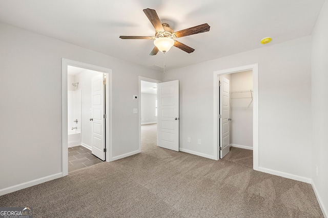 unfurnished bedroom featuring a ceiling fan, a closet, carpet, baseboards, and a spacious closet
