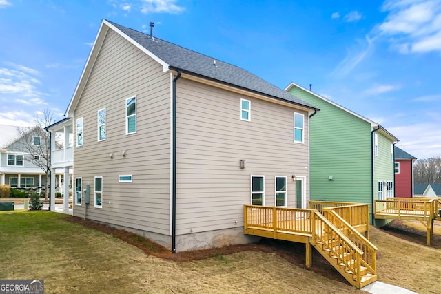 rear view of property with stairway, a wooden deck, and a yard