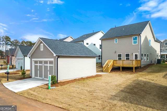 rear view of property featuring central AC unit, an attached garage, concrete driveway, stairway, and a wooden deck
