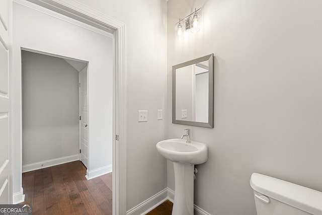 half bath with toilet, baseboards, and wood finished floors