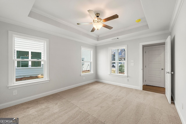 carpeted empty room featuring a tray ceiling, crown molding, baseboards, and ceiling fan