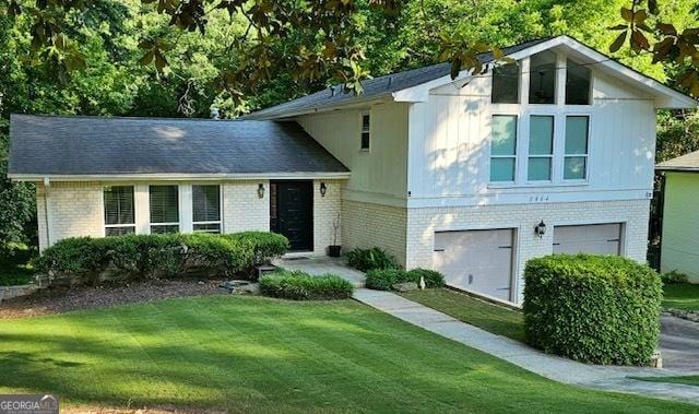 split level home with brick siding, a front yard, and a garage