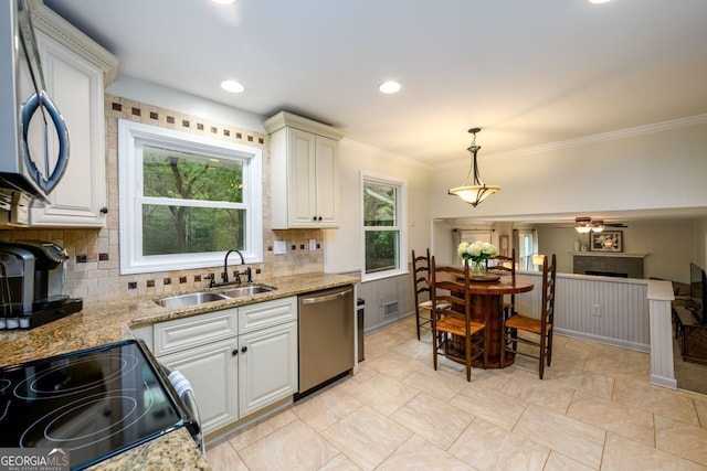 kitchen featuring appliances with stainless steel finishes, a sink, a fireplace, tasteful backsplash, and decorative light fixtures