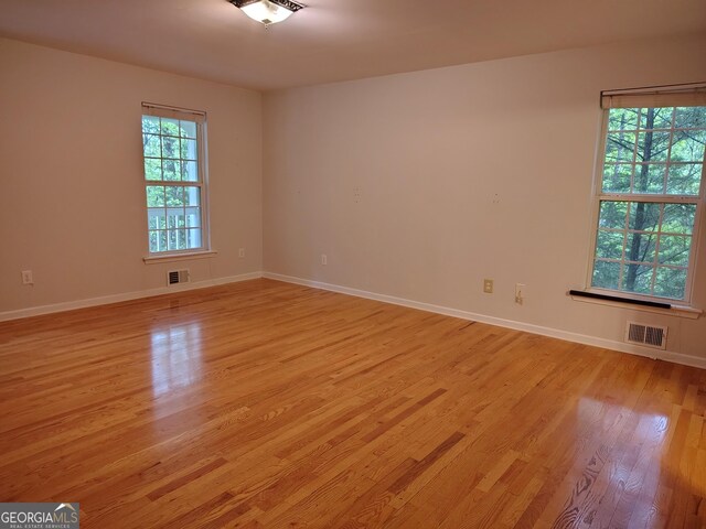 empty room featuring baseboards, visible vents, and light wood-type flooring