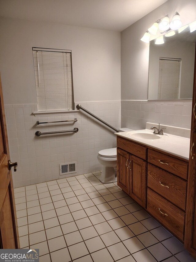 bathroom featuring tile walls, toilet, visible vents, tile patterned flooring, and vanity