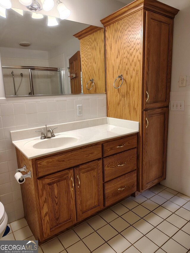 bathroom featuring toilet, tile walls, tile patterned flooring, a shower stall, and vanity